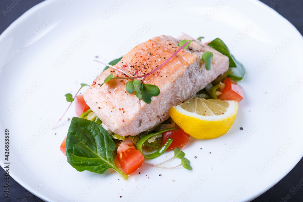 Trout (salmon) with vegetables, lemon and microgreens, cooked by the confit method. Traditional French dish. Step by step. Close-up. Trout (salmon) with vegetables, lemon and microgreens, cooked by the confit method. Traditional French dish. Step by step. Close-up.