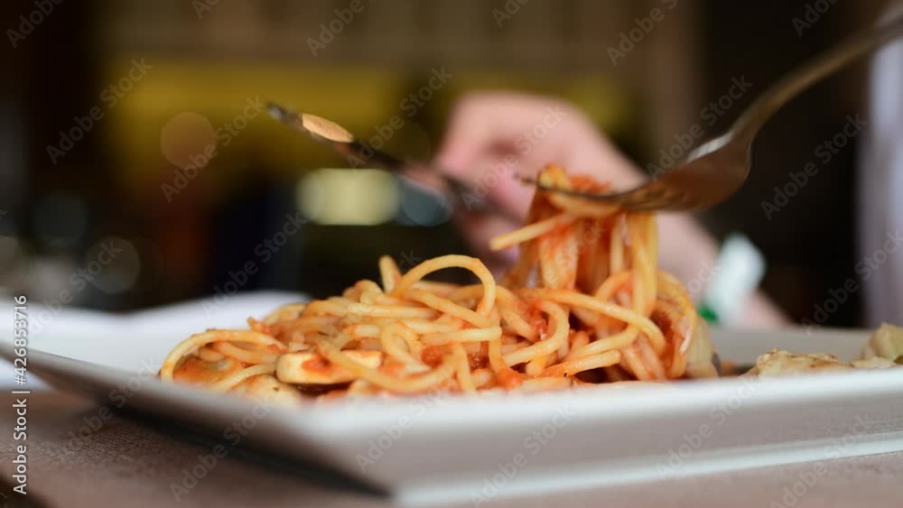 Teenager's hand winding spaghetti on a fork