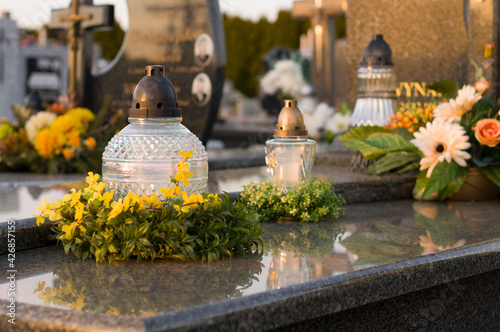 A tomb decorated with candles and flowers with cementary in the background.