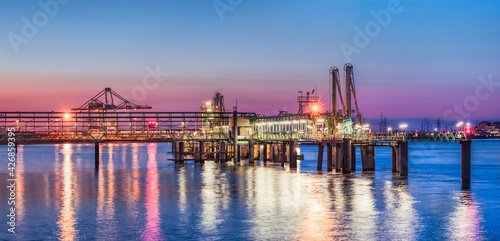 Industrial pier near petrochemical production plant during a colorful sunset, Port of Antwerp, Belgium