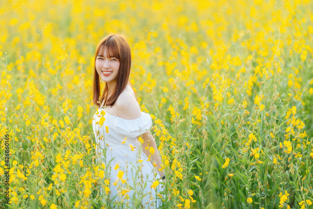 Happy young woman wear white dress walking in yellow flowers field. Happy young woman wear white dress walking in yellow flowers field.