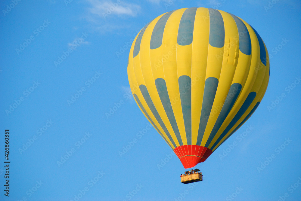Fototapeta premium Yellow hot air balloon flying in the blue sky of Cappadocia.