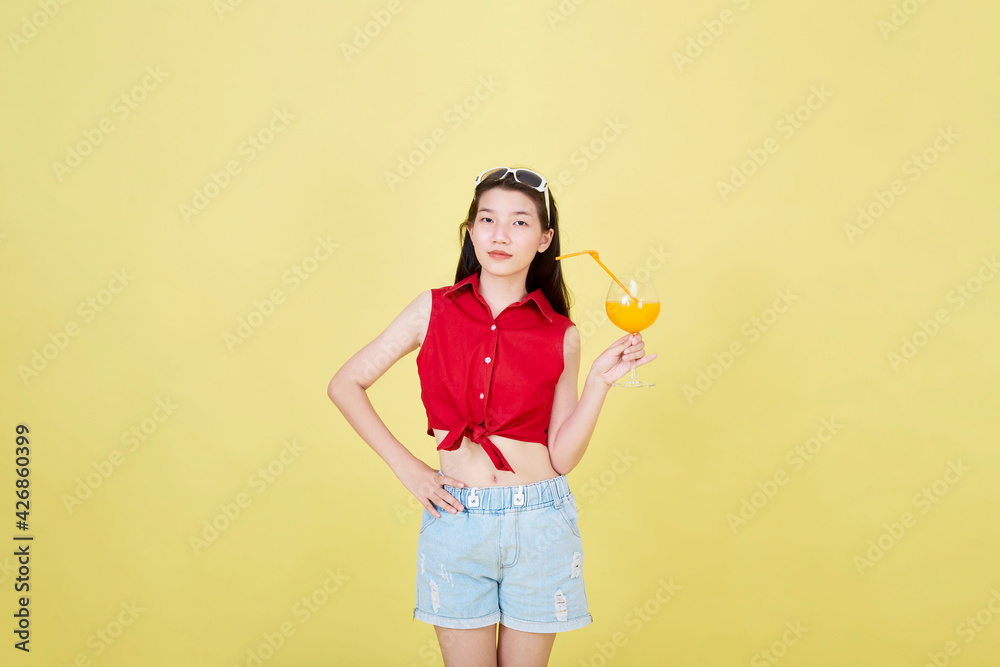 Woman drinking juice in summer on yellow background Woman drinking juice in summer on yellow background