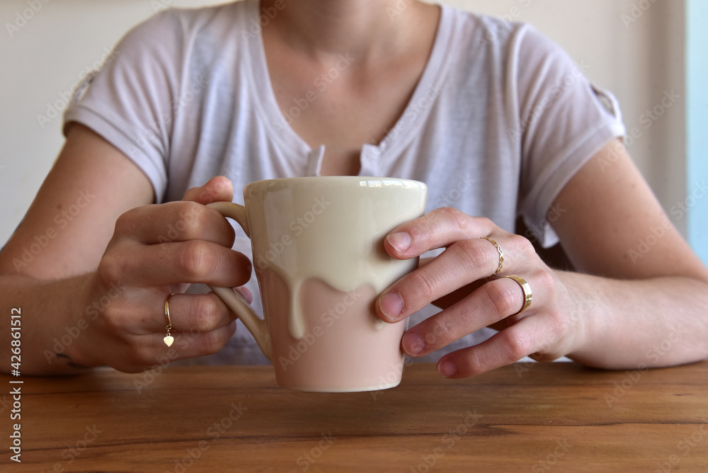 Woman holding cup of coffee with milk and cinnamon powder. Woman holding cup of coffee with milk and cinnamon powder.