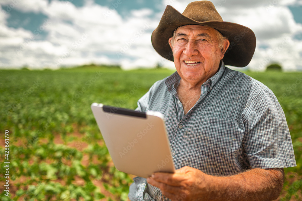Latin American Farmer working on soybean plantation, examining crop development on tablet