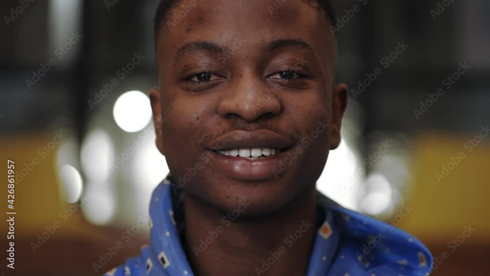 Close up view of young cheerful afro american man looking to camera. Portrait of handsome male person with neckerchief posing and laughing in cafe. Blurred background. Close up view of young cheerful afro american man looking to camera. Portrait of handsome male person with neckerchief posing and laughing in cafe. Blurred background.