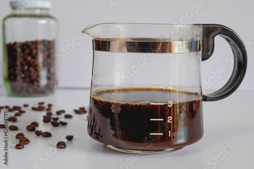 Coffee jar glass with cup and coffee maker on background.