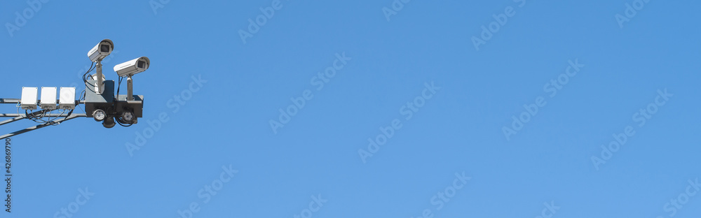 CCTV cameras on the background of a clear blue sky. Banner, copy space. Control and safety equipment. Video surveillance system and fixing violations CCTV cameras on the background of a clear blue sky. Banner, copy space. Control and safety equipment. Video surveillance system and fixing violations