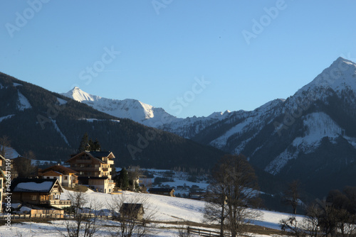 Skiing lodges in front of snowy mountains on a sunny spring day