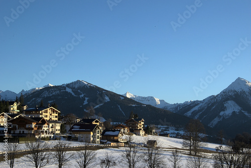 Skiing lodges in front of snowy mountains in spring