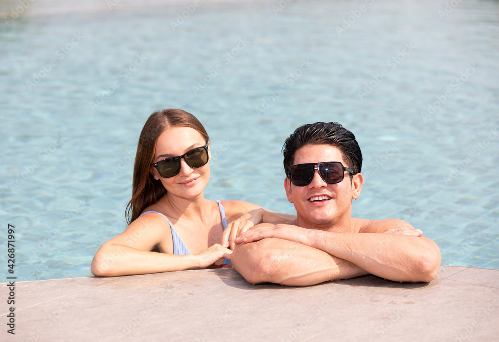 portrait couple wearing sunglasses, and enjoy each other in swimming pool portrait couple wearing sunglasses, and enjoy each other in swimming pool