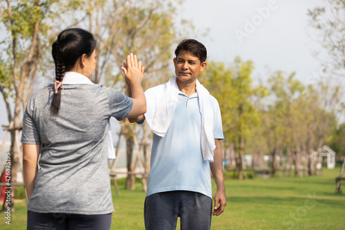 senior asian man taking high five with hands after jogging in public park