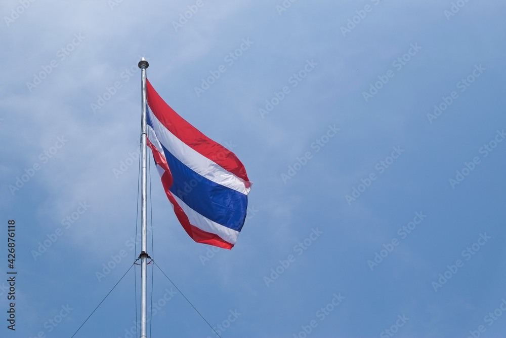 National Thailand flag blowing with wind on top flag pole and blue sky.