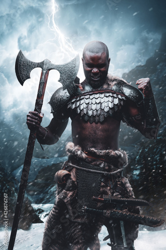 Nordic barbarian with black skin and axe in snowstorm in mountains