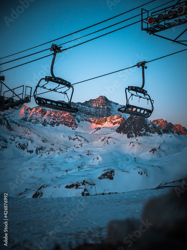 télésiège à l’arrêt à Tignes, en Savoie, avec la montagne au loin et le lever du soleil.