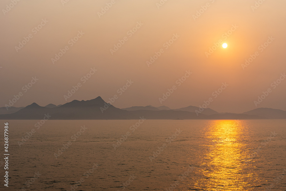 Beautiful sunrise above Chinese sea coast near Xiamen, foggy morning on golden hour.