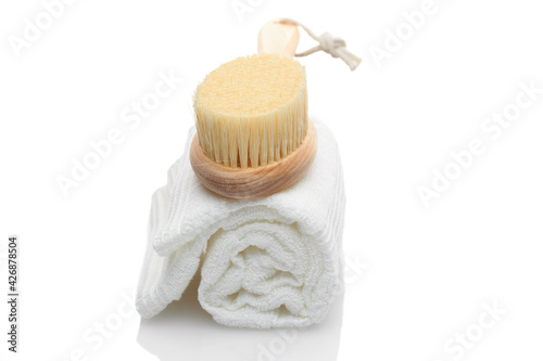 A dry massage brush made of natural materials and a cotton towel on a white background. Cleanliness and body care concept