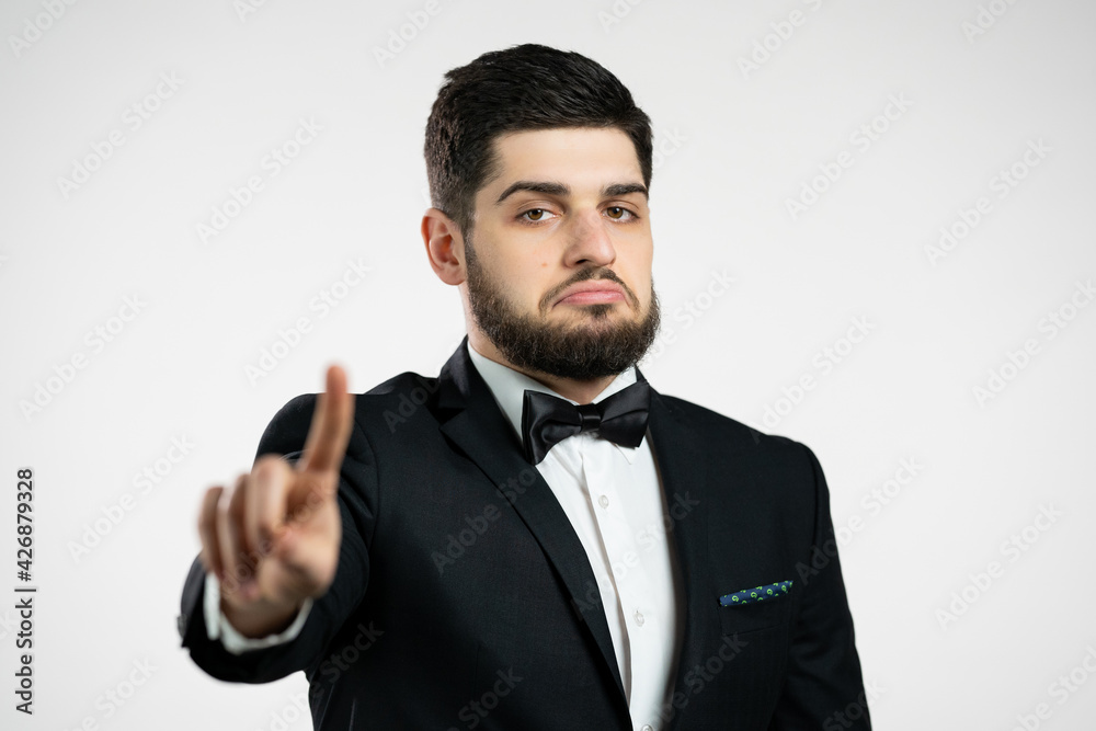 Portrait of serious man in black tuxedo showing rejecting gesture by stop finger sign. Guy isolated on white background. Portrait of serious man in black tuxedo showing rejecting gesture by stop finger sign. Guy isolated on white background.