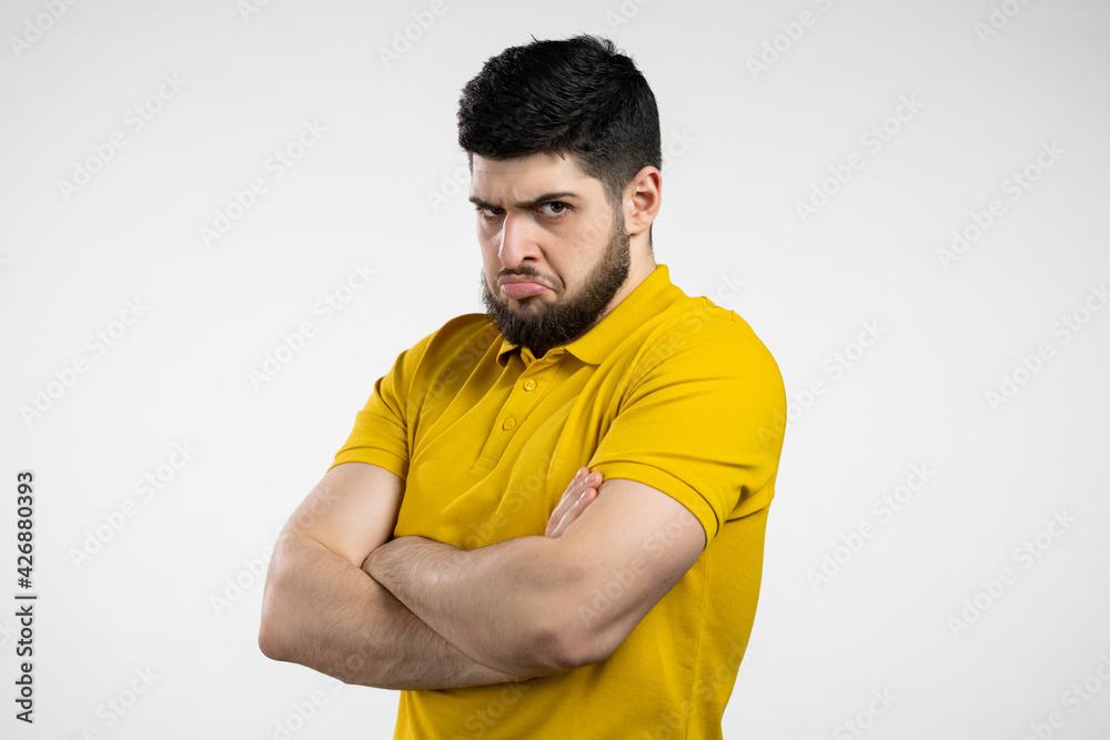 Angry offended man keeping arms crossed and staring at camera with sceptical and distrustful look, feeling mad at someone. Human facial expressions, emotions and feelings. Body language Angry offended man keeping arms crossed and staring at camera with sceptical and distrustful look, feeling mad at someone. Human facial expressions, emotions and feelings. Body language