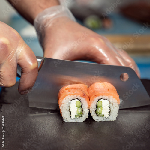 Chef cutting the Philadelphia light sushi roll close up