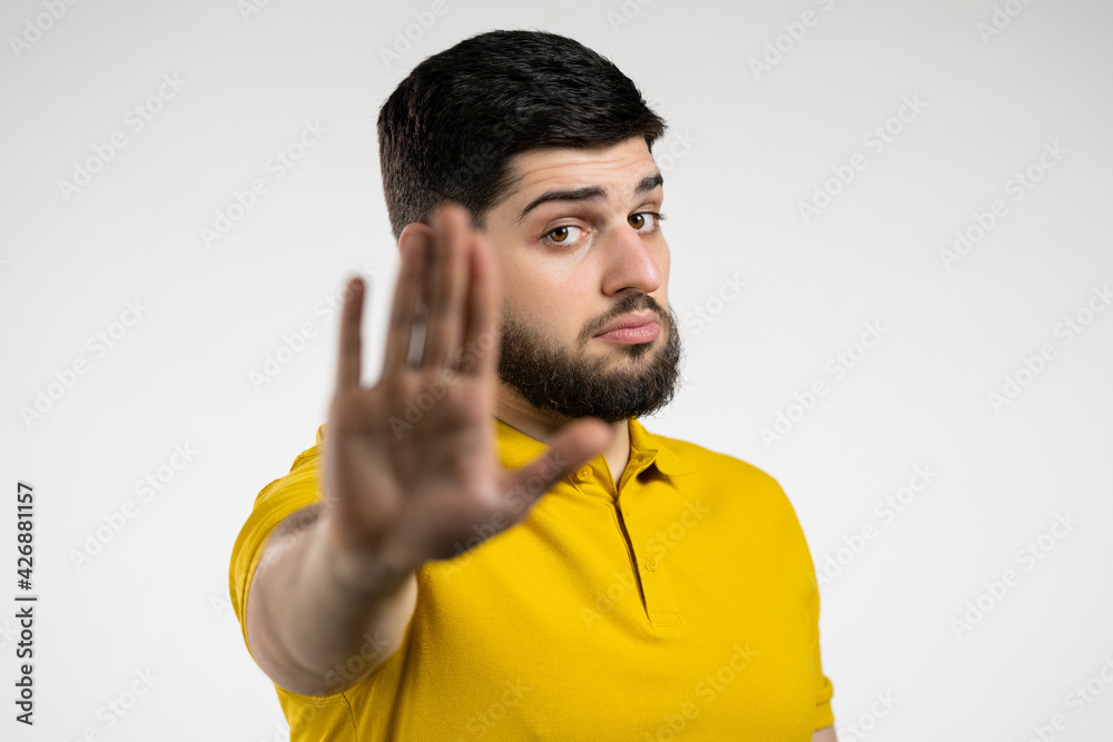 Portrait of serious man disapproving with no palm hand sign make basta, negation, enough gesture. Denying, Rejecting, Disagree. Portrait of handsome guy on white background Portrait of serious man disapproving with no palm hand sign make basta, negation, enough gesture. Denying, Rejecting, Disagree. Portrait of handsome guy on white background