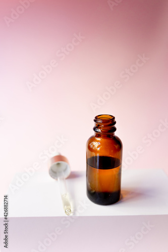Essential oil serum glass pipette and bottle on pink background. Natural Serums. Cosmetic concept. photo