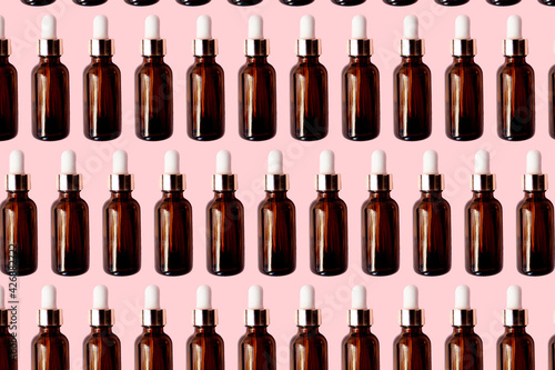Essential oil serum glass bottle pattern isolated on pink background. Natural Serums. Cosmetic concept. photo