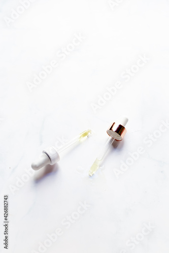 Retinol oil serum oil pipettes on isolated marble background. Beauty care concept. photo
