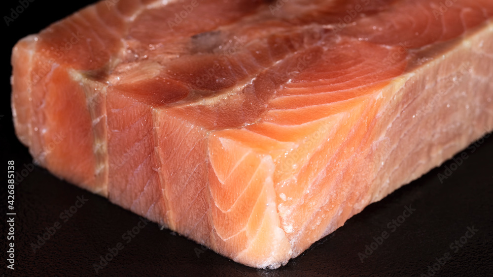 Cube piece of raw pink salmon fish on black background