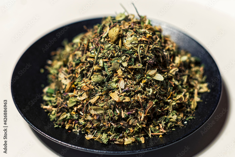 Dried herbs, a soothing herbal collection on a black plate on a white background Dried herbs, a soothing herbal collection on a black plate on a white background