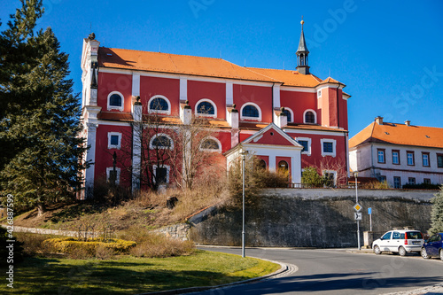 Medieval baroque red and white Church of the Holy Trinity, Chapel near castle, Thun's tomb, sunny day, old historic town, blue sky, Klasterec nad Ohri, Bohemia, Czech Republic photo