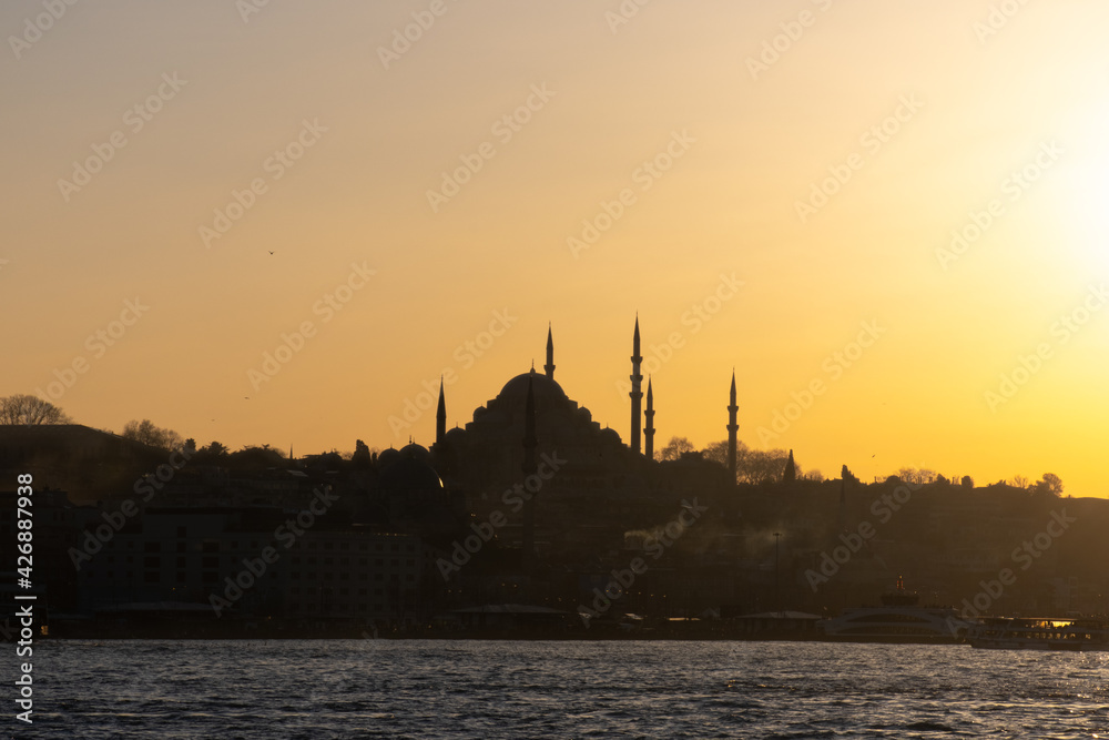 Sunset with sun behind silhouette in istanbul, golden horn suleymaniye mosque