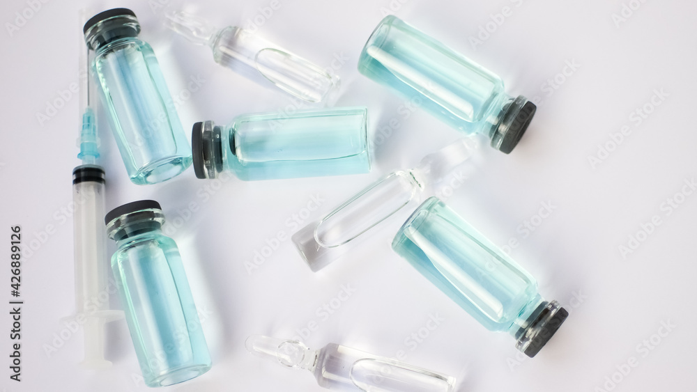 Vial vaccine, top view of glass ampoules with transparent and blue liquid lying on white background, global vaccination concept Vial vaccine, top view of glass ampoules with transparent and blue liquid lying on white background, global vaccination concept