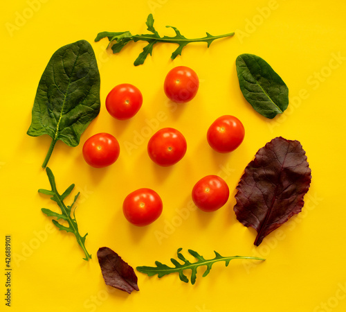 Fototapeta Naklejka Na Ścianę i Meble -  Cherry tomatoes, beet leaves, spinach leaves and arugula leaves on a yellow background