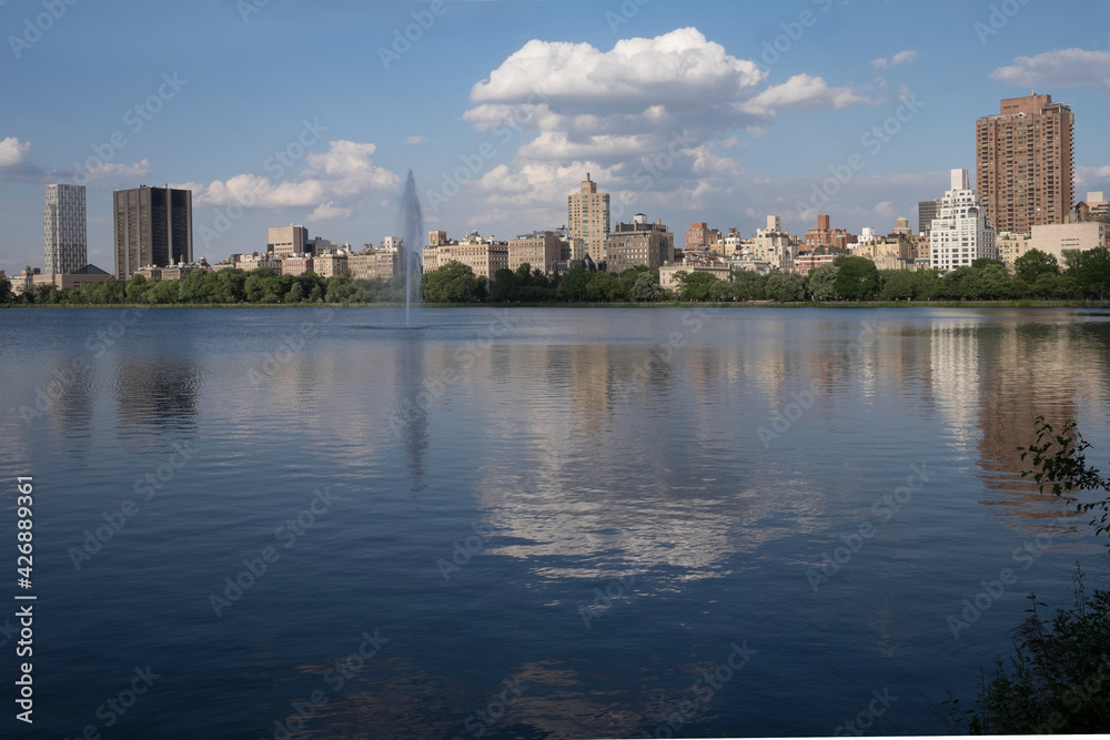 Buildings and clouds reflection in Central Park late in the afternoon in midtown Manhattan in New York City. Space tor text on water