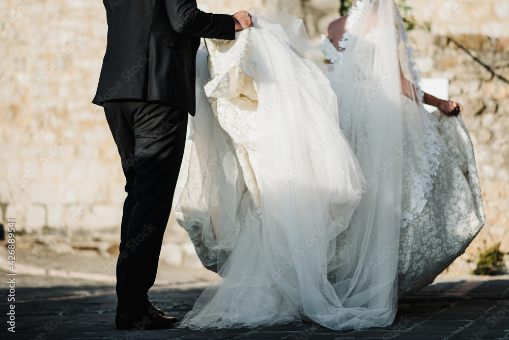 groom helps the bride to carry a white wedding dress on wedding day groom helps the bride to carry a white wedding dress on wedding day