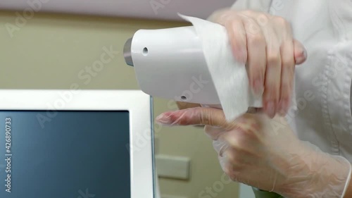 a woman disinfects a manipulator, in the laser hair removal room
