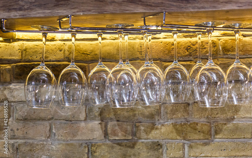 Rows of empty wine glasses on the showcase in the restaurant or bar. Table setting, close up. Glasses for alcohol. photo