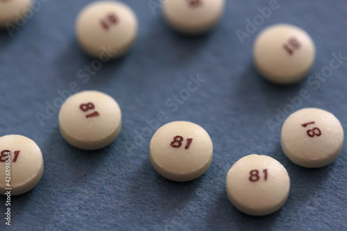 scattered low dose 81 milligrams aspirin on a slate blue gray background with a low depth of field, commonly used as a preventive medicine for heart disease with copy space