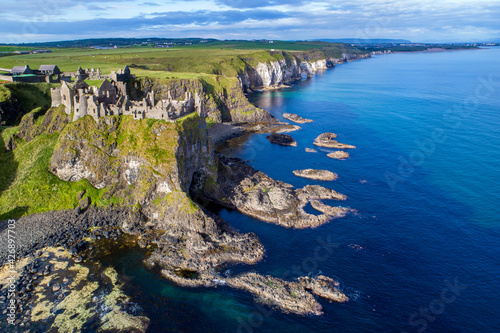 Ruins of medieval Dunluce Castle, cliffs, bays and peninsulas. Northern coast of County Antrim, Northern Ireland, UK.  Aerial view. photo