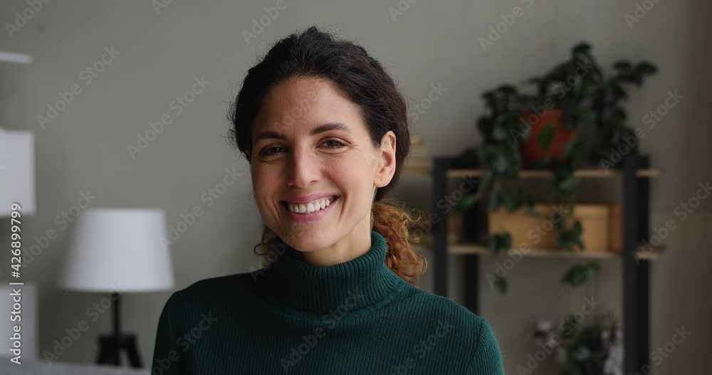 Close up head shot pretty nice millennial caucasian woman looking at camera, showing perfect white healthy toothy smile, posing in own apartment, feeling satisfied, enjoying carefree time indoors.