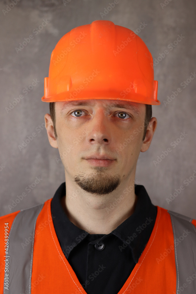Portrait of a young handsome man worker or engineer in helmet and yellow vest on gray background Portrait of a young handsome man worker or engineer in helmet and yellow vest on gray background