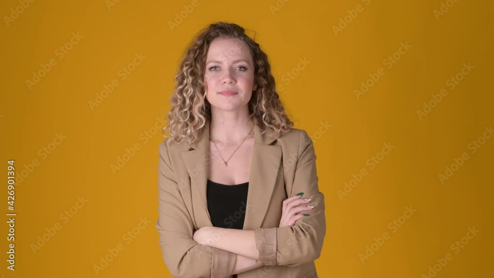 Portrait of joyful young woman with curly hair smiling and looking at the camera isolated on yellow background. People sincere emotions lifestyle concept. Emotions. Portrait of joyful young woman with curly hair smiling and looking at the camera isolated on yellow background. People sincere emotions lifestyle concept. Emotions.