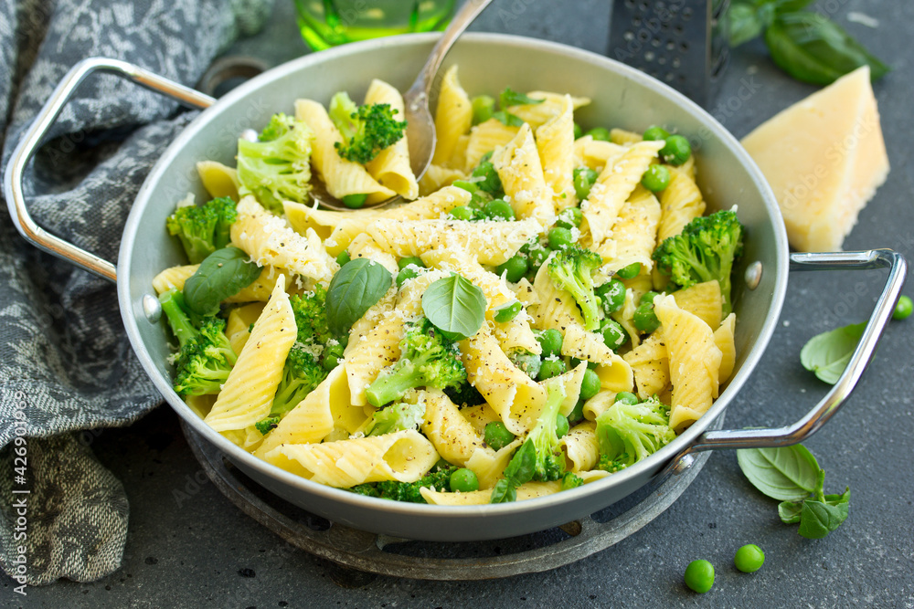 penne pasta with spinach pesto sauce, green peas and broccoli, top view penne pasta with spinach pesto sauce, green peas and broccoli, top view