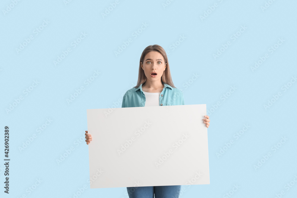 Surprised young woman with blank poster on color background Surprised young woman with blank poster on color background