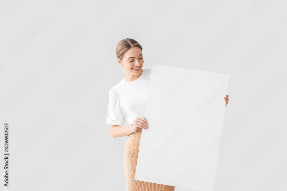 Beautiful young woman with blank poster on light background Beautiful young woman with blank poster on light background