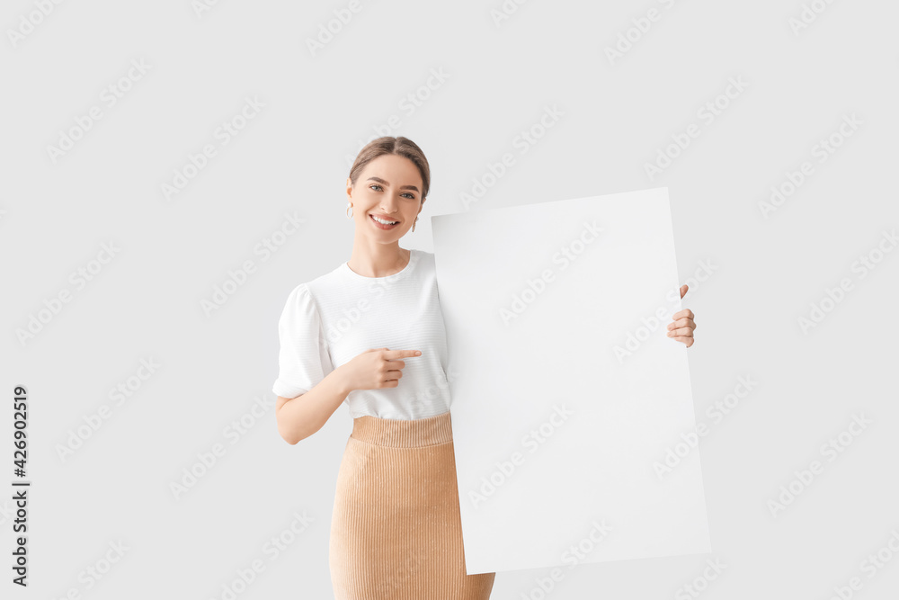 Beautiful young woman with blank poster on light background Beautiful young woman with blank poster on light background