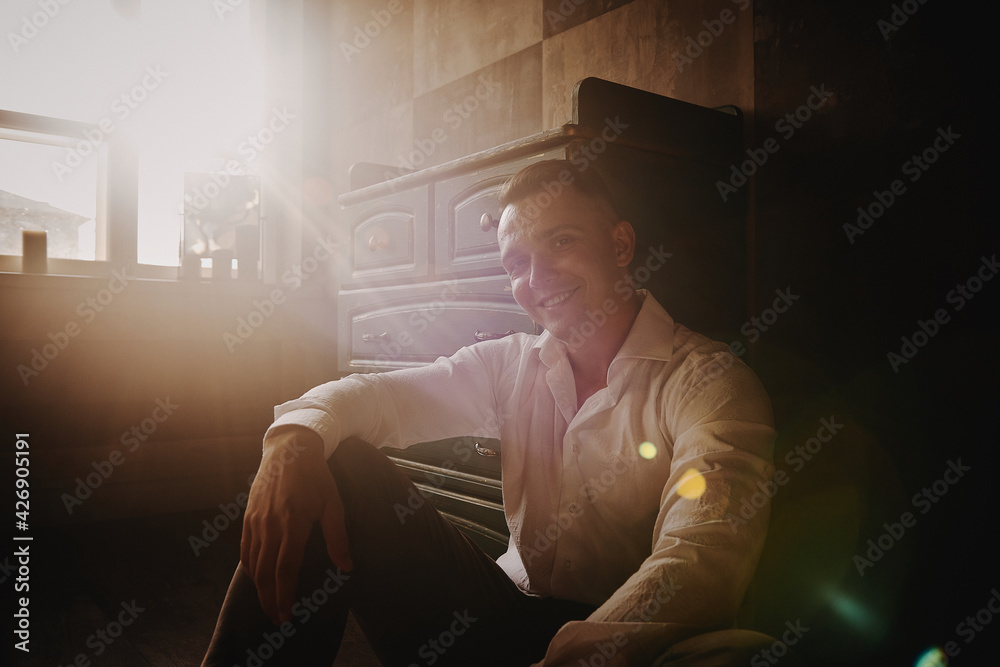 The man sits next to the wall looking forward, the room is dim The man sits next to the wall looking forward, the room is dim