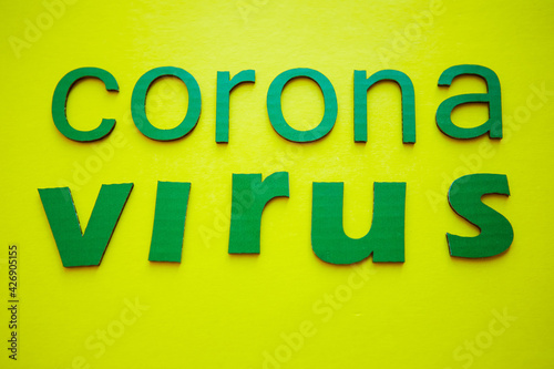 Word CORONAVIRUS made of green cardboard letters, isolated on yellow background. World Health Organization WHO introduced new official name for Coronavirus disease named COVID-19