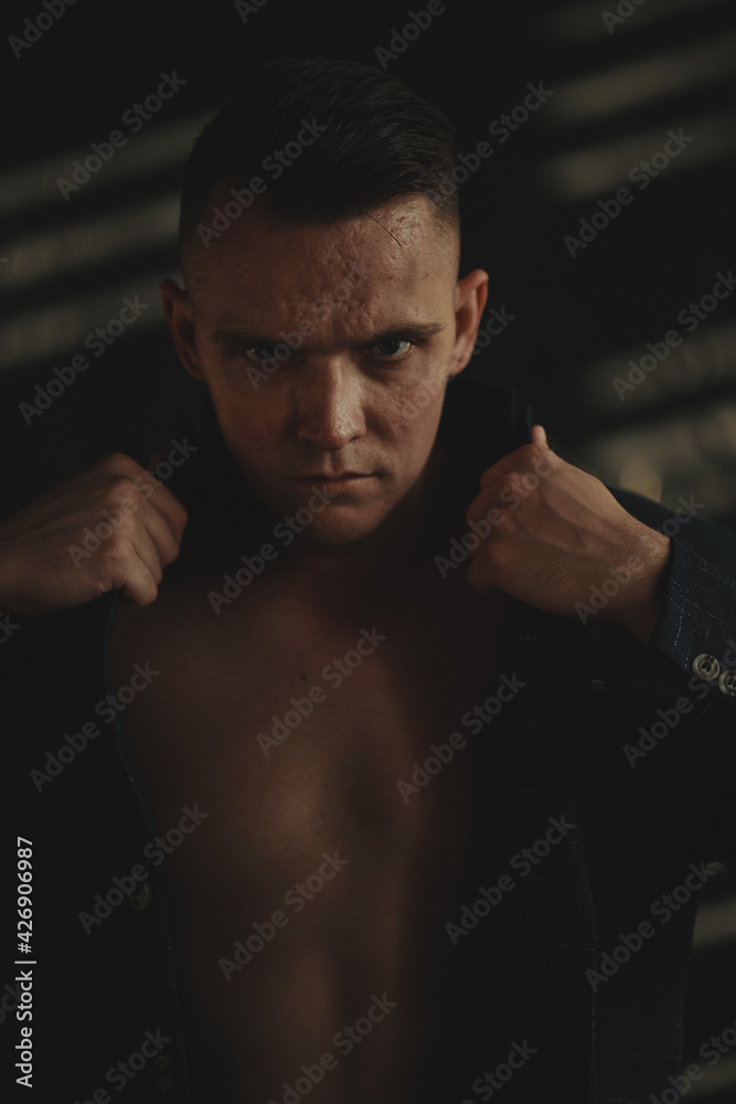 Obraz premium The man sits next to the wall looking forward, the room is dim
